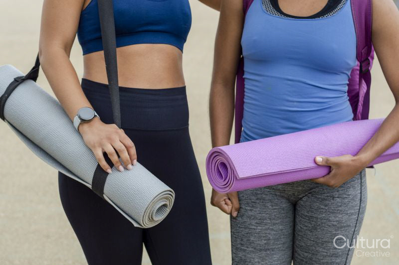 Female friends holding yoga mats