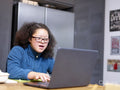 Girl with Down Syndrome using laptop in kitchen