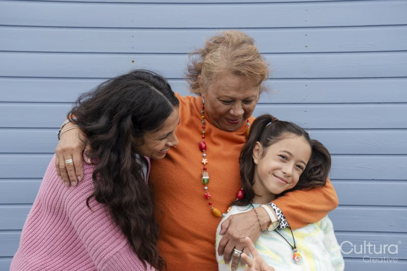 Portrait of grandmother, mother and granddaughter against blue wall
