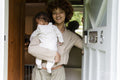 Smiling mother holding baby daughter at home entrance