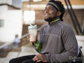Smiling athletic man with protein drink outdoors