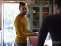 Man washing dishes while boyfriend using digital tablet at home kitchen