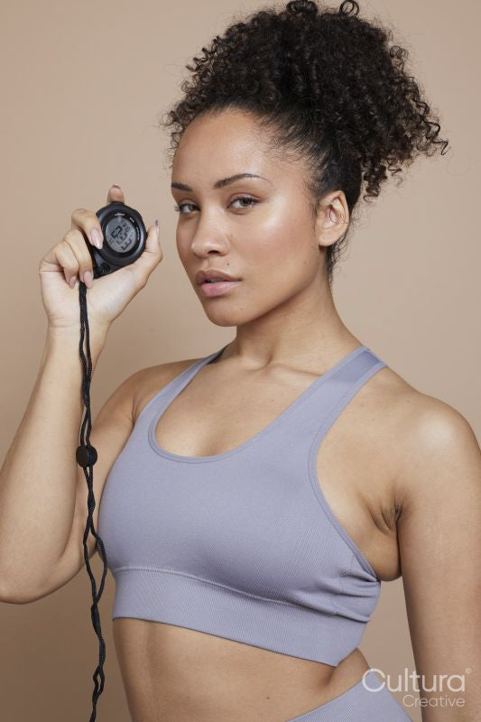 Studio portrait of athletic woman holding digital stopwatch
