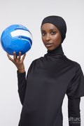Studio portrait of young woman in hijab holding soccer ball