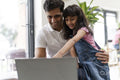 Father sitting with daughter and using laptop