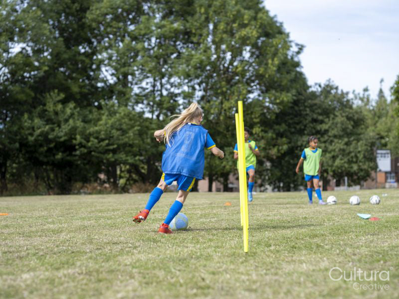 Children dressed in uniforms practicing on soccer field