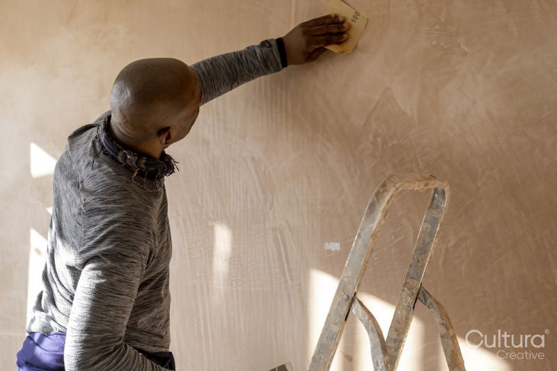 Man sanding wall in house