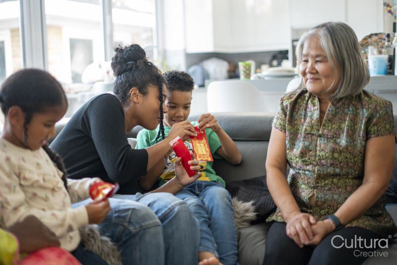 Family gathered in living room, sharing red envelopes