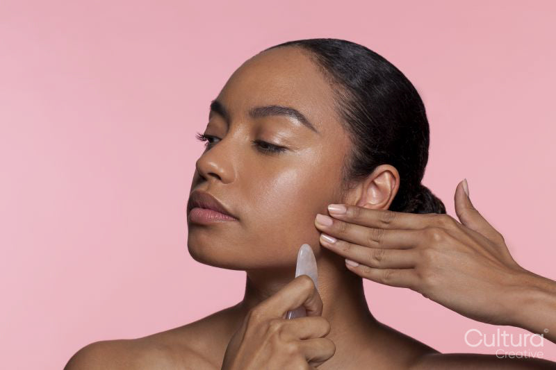 Young woman using face massager