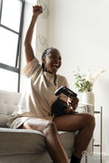 Excited young woman playing video games while sitting on sofa at home
