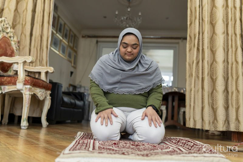 Muslim woman with down syndrome praying at home