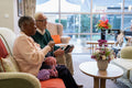 Smiling senior man and woman relaxing on sofa in nursing home