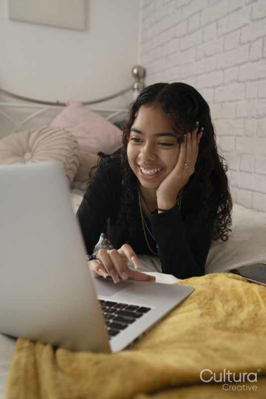 Teenage girl using laptop on bed at home
