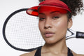 Studio portrait of woman with tennis rocket and red sunvisor