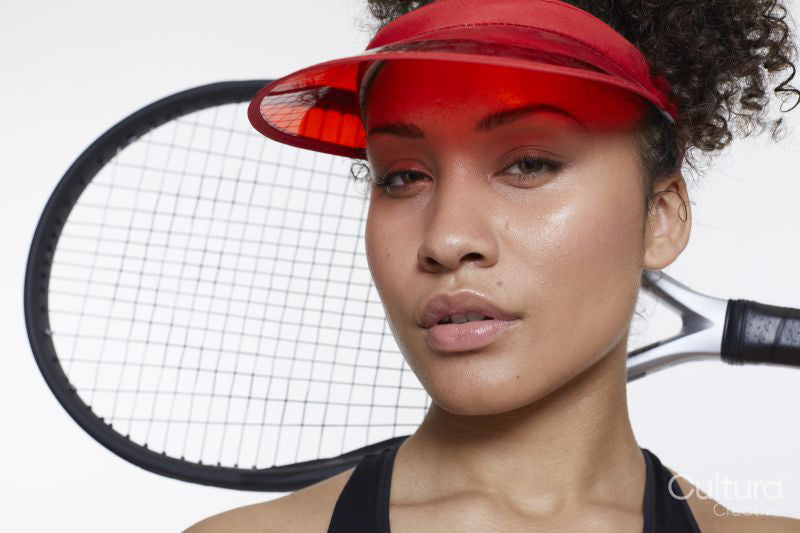 Studio portrait of woman with tennis rocket and red sunvisor
