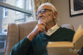 Senior man sitting in armchair and reading book