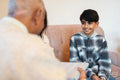Mother and son giving birthday gift to senior man in nursing home
