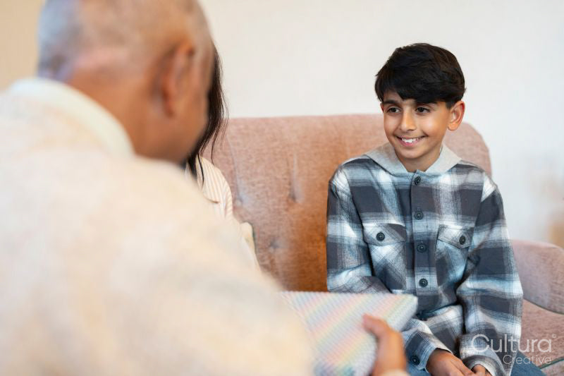 Mother and son giving birthday gift to senior man in nursing home
