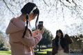 Young woman photographing friend in park