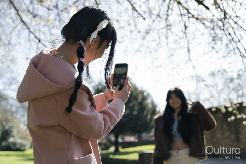 Young woman photographing friend in park