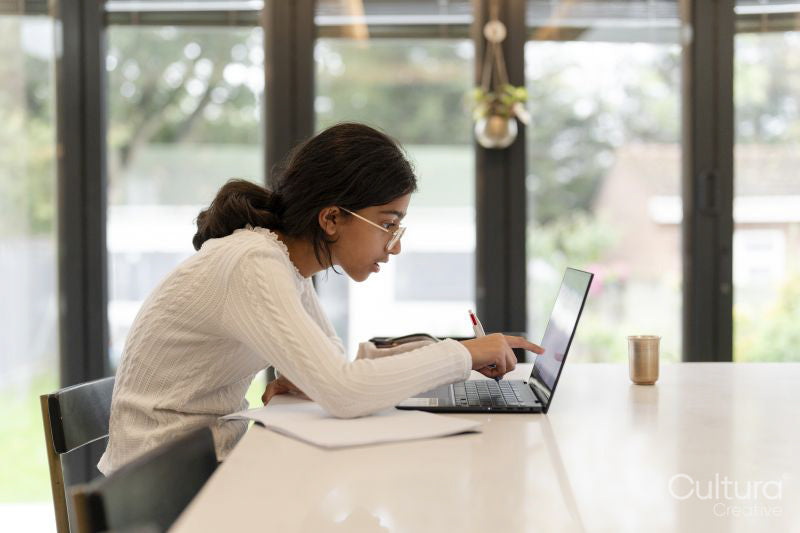 Girl doing homework and using laptop in living room
