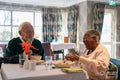 Smiling senior people eating meal in nursing home