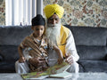 Grandfather and grandson in traditional clothing reading book