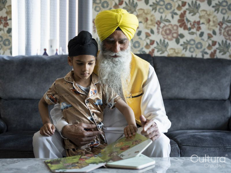Grandfather and grandson in traditional clothing reading book