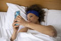 Woman looking at smart phone in bed