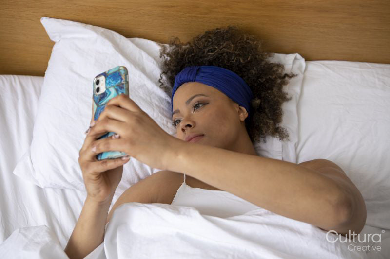 Woman looking at smart phone in bed