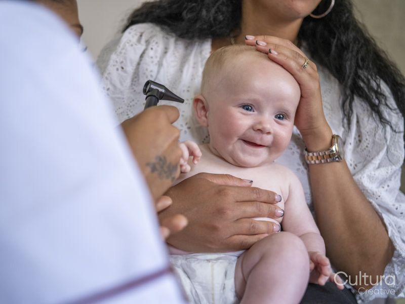 Nurse examining baby girl with otoscope