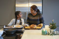 Smiling mother and daughter preparing roasted turkey in kitchen