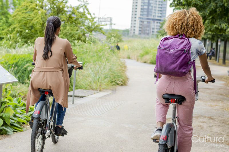 Rear view of two women cycling together in city