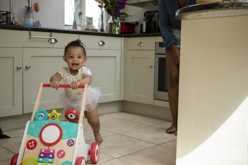 Baby girl using walker at home
