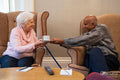 Senior man handing tea cup to senior woman in nursing home