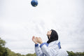 Woman in hijab sitting throwing soccer ball