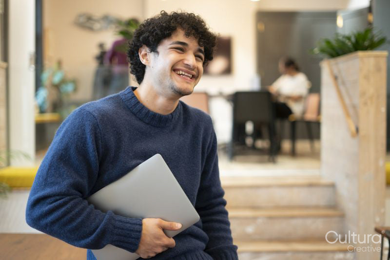Smiling businessman holding laptop in office