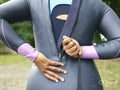 Rear view of woman putting on wetsuit