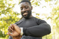 Smiling athletic man checking smart watch in park
