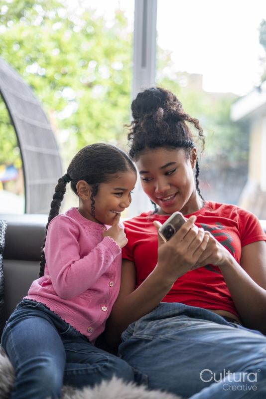 Two girls sitting on sofa looking at smartphone