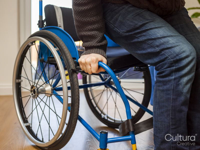 Mid section of disabled man sitting on wheelchair at home