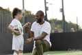 Man instructing girl with ball on soccer field