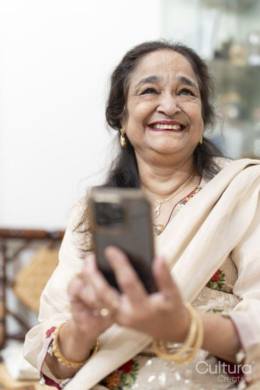 Portrait of senior woman laughing while using smart phone in living room