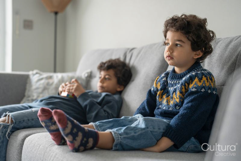 Brothers sitting on sofa an watching TV