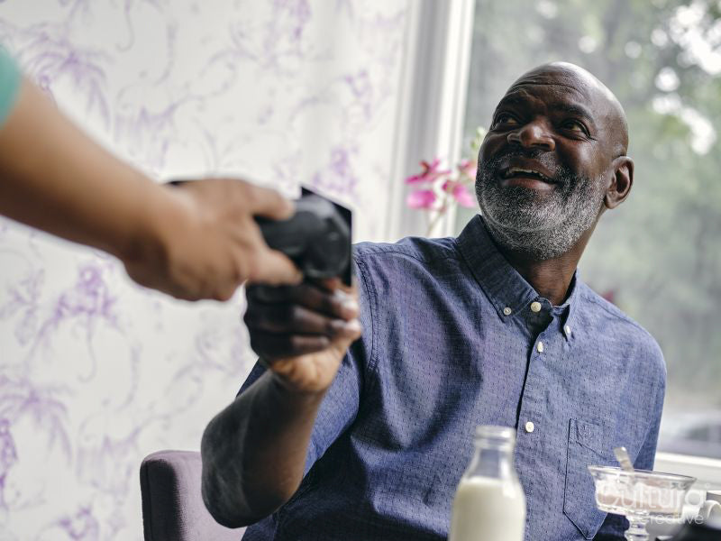 Smiling man paying with smart phone at cafe table
