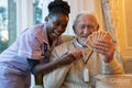 Smiling senior man and nurse playing cards at table in nursing home