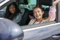 Smiling mother and daughter sitting in car