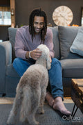 Man with dreads sitting on sofa and petting dog