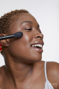 Studio portrait of smiling woman applying blush