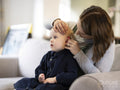 Mother adjusting daughters hearing aid at home